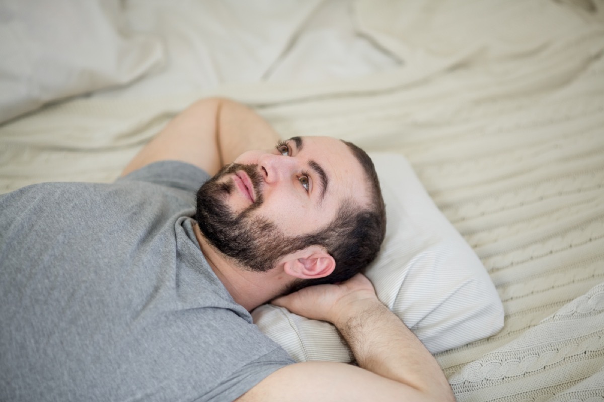 young white man on bed with eyes open