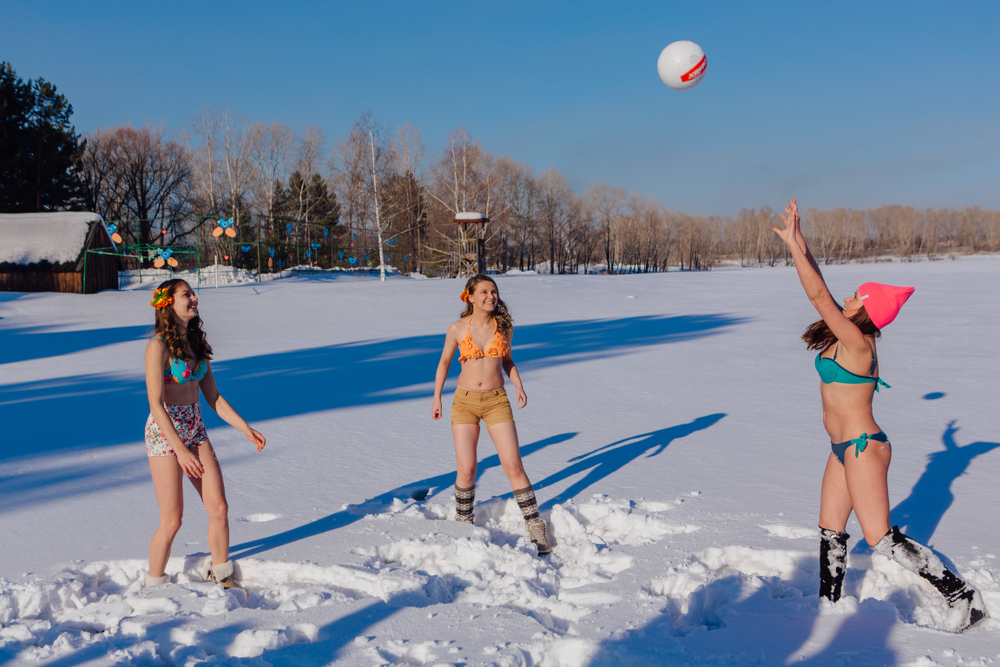 women in bikinis playing volleyball in snow