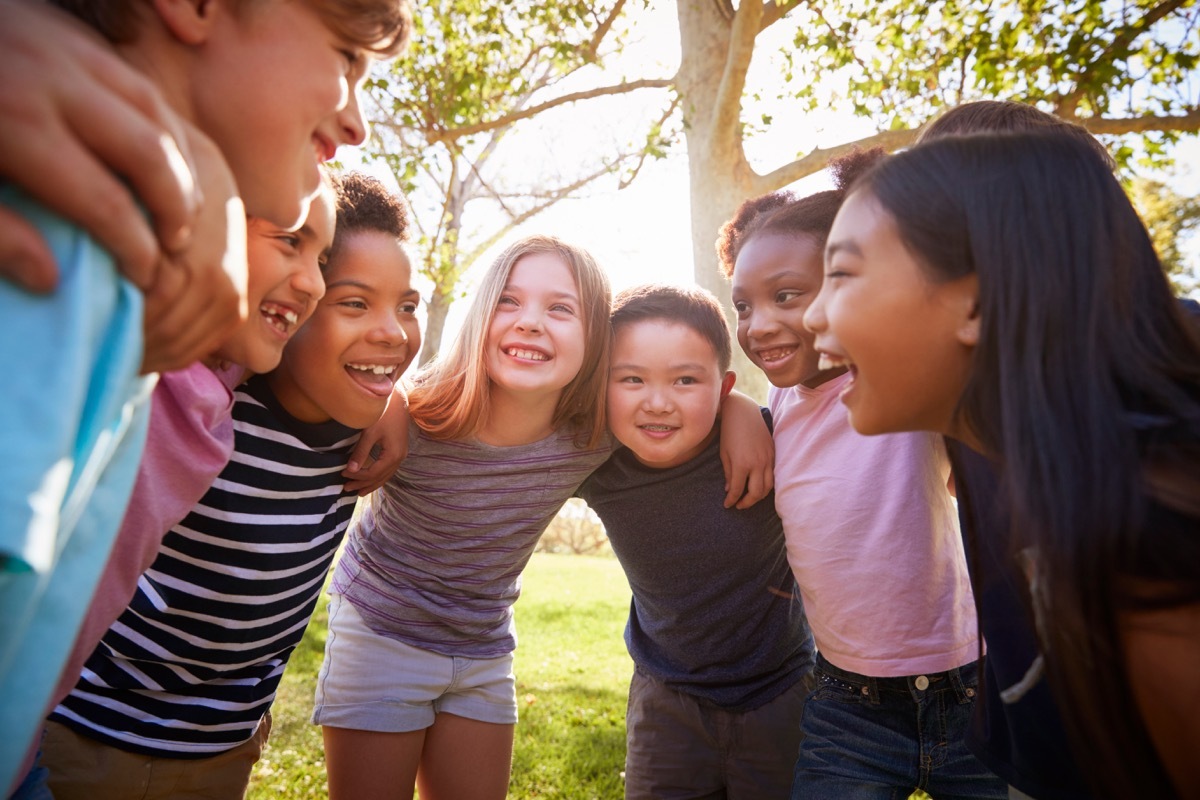 Kids in a huddled circle smiling and laughing