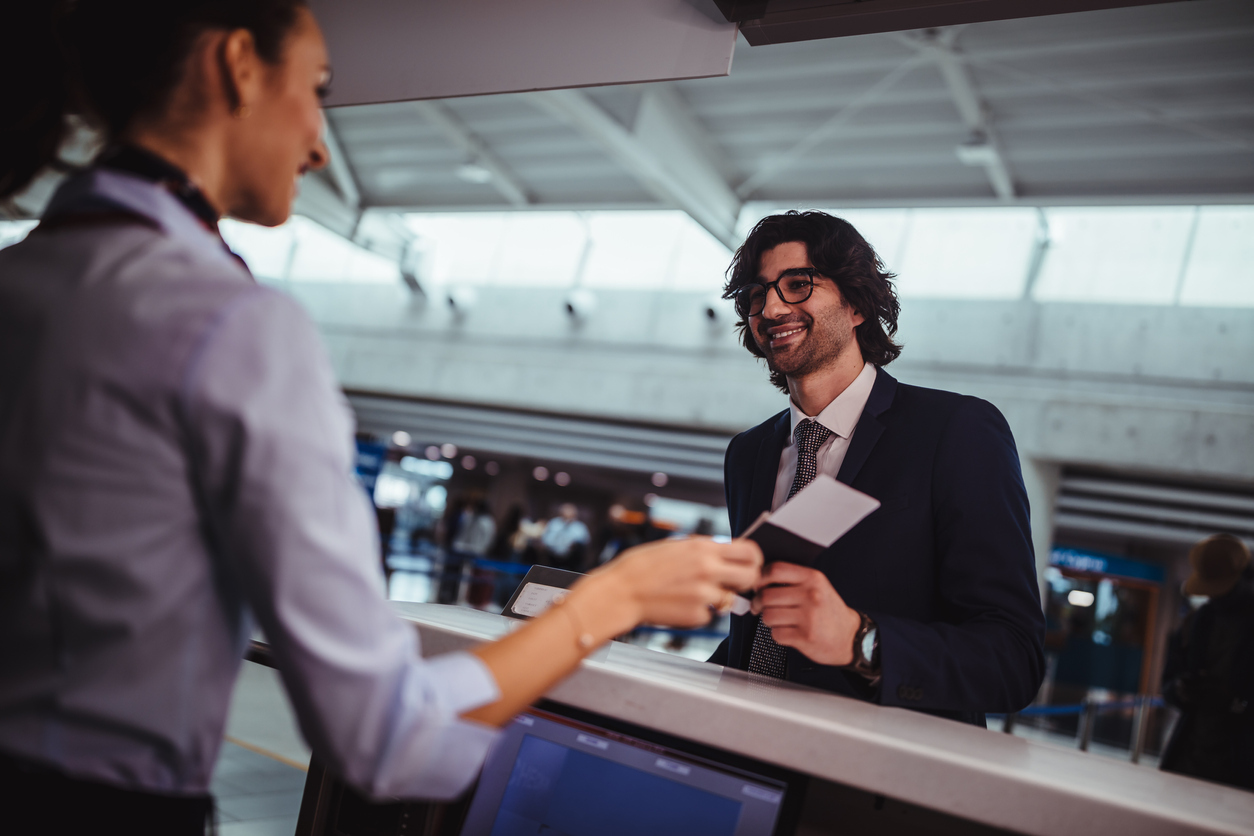 A man handing a boarding pass or plane ticket to a gate agent at the airport