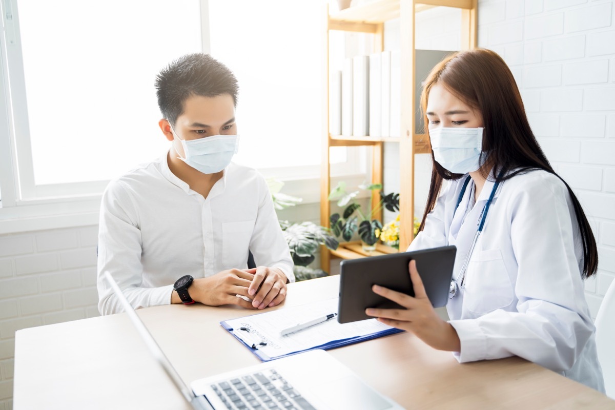 young doctor talking to patient and showing him an ipad