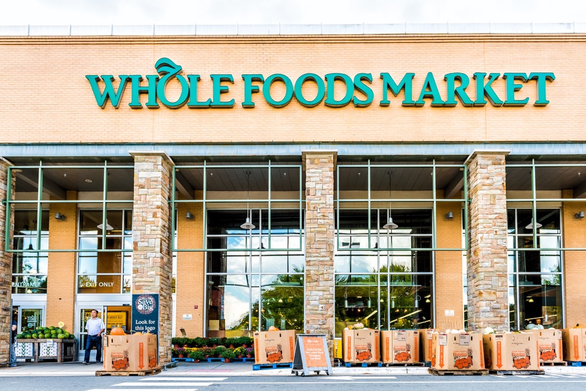 Fairfax, USA - September 8, 2017: Green Whole Foods Market grocery store sign on exterior building in city in Virginia with autumn displays of pumpkins for Halloween