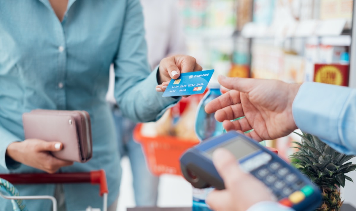 Woman at the supermarket checkout, she is paying using a credit card