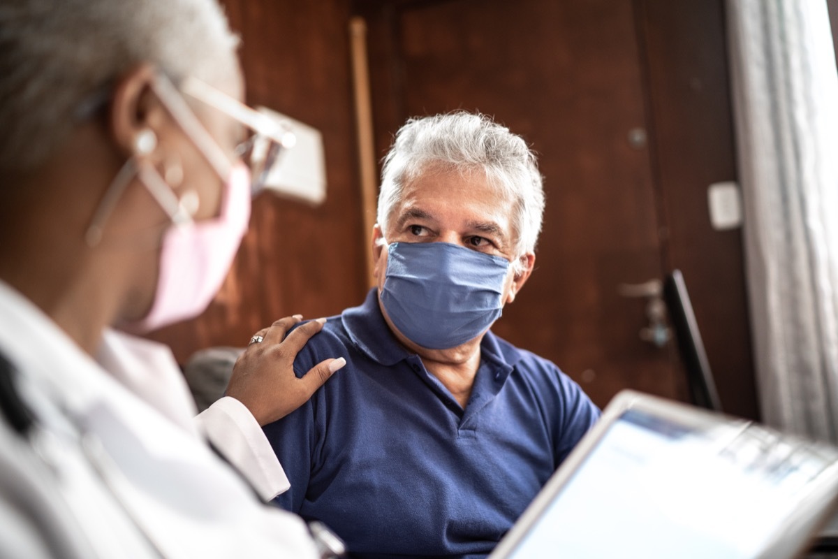 Doctor talking to senior male patient in a home visit