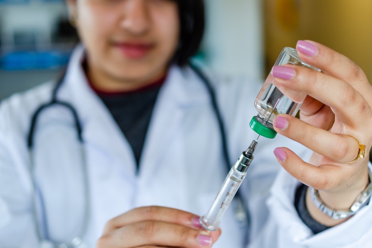 Woman health care personel drawing medicine in syringe