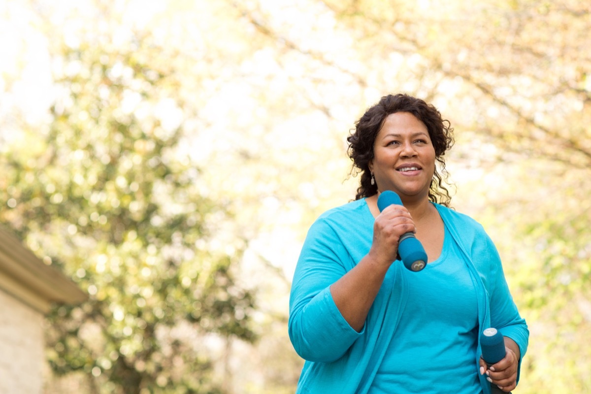 Older black woman walking and exercising with weights in her hands