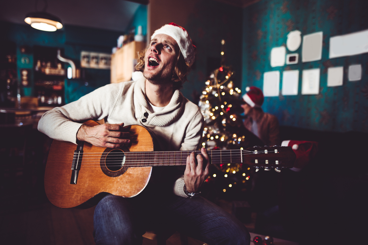 young man singing and playing guitar at home