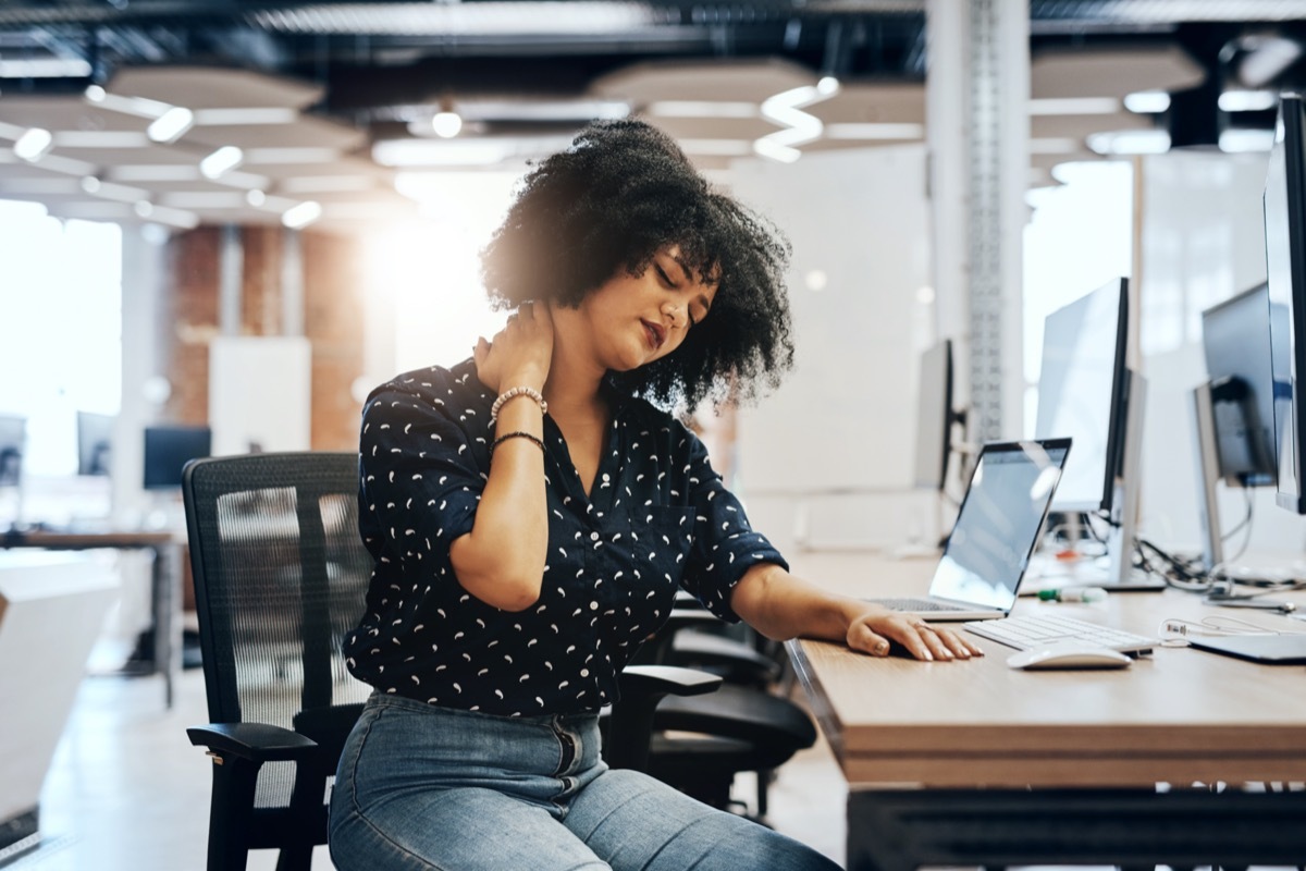 Shot of a young female designer experiencing neck pain and discomfort while sitting at her office desk