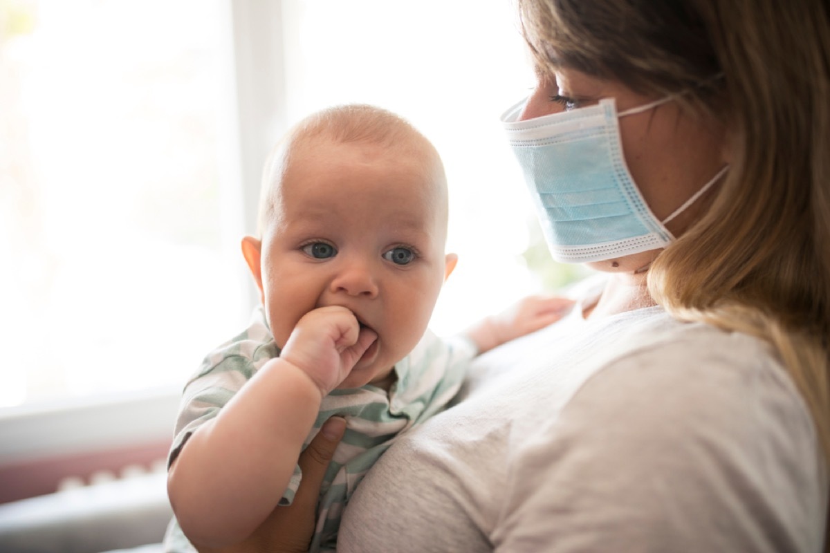 baby with mother wearing face mask