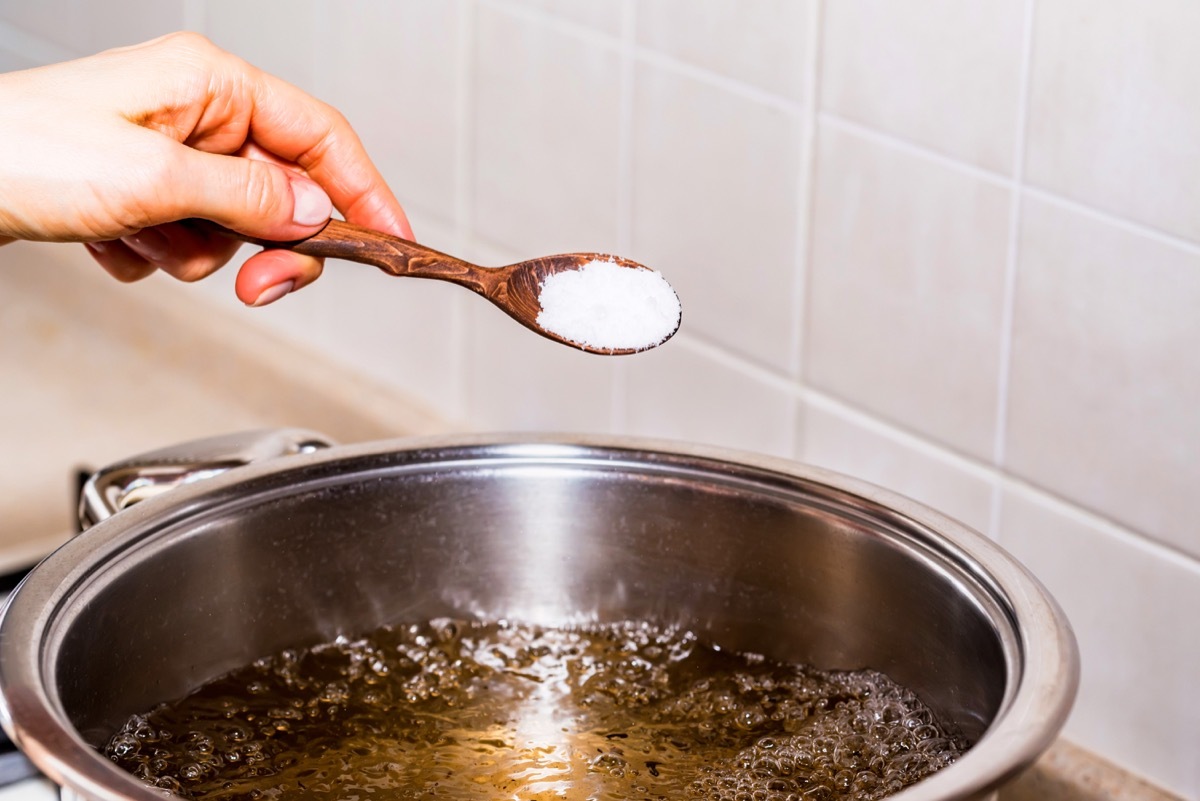 woman adding salt to boiling water