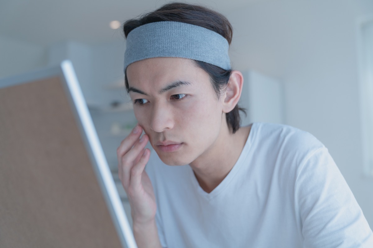 Man looking at his dry skin in the mirror