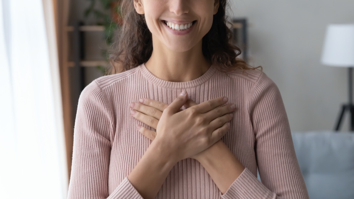 female holding folded hands on chest