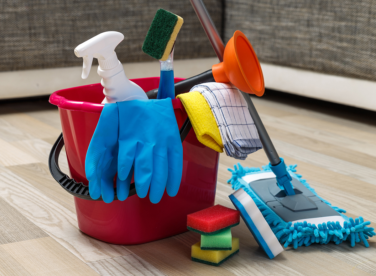 Bucket full of cleaning products on wooden floor