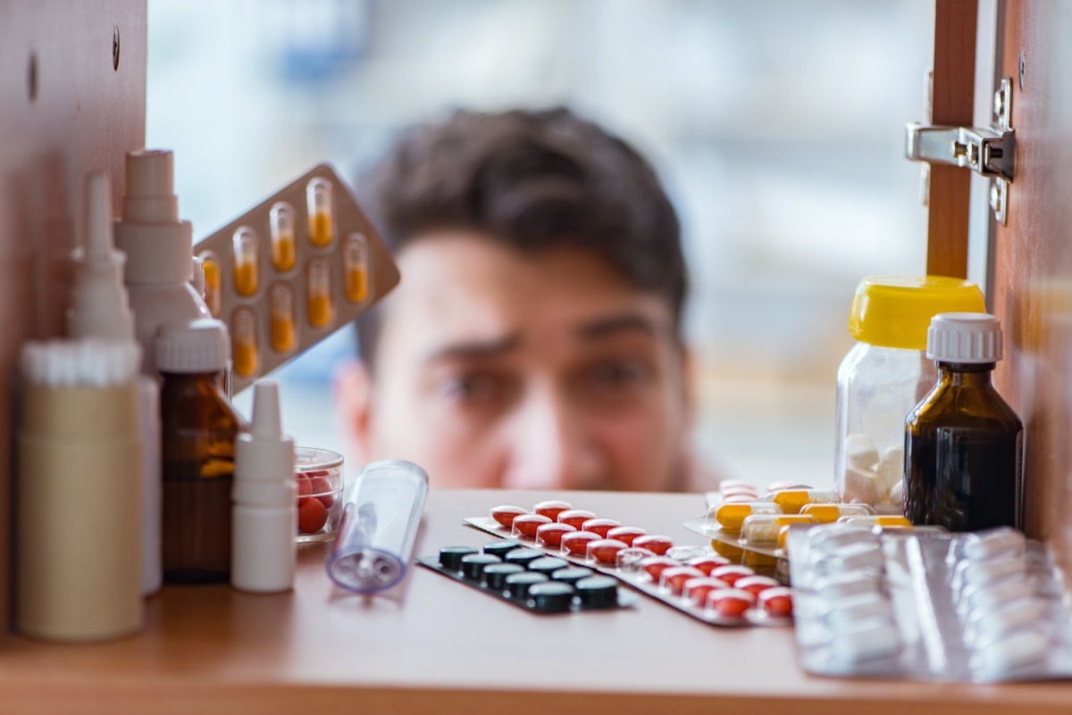 Sick man looking at shelf full of medicine