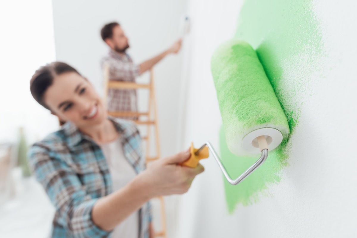 Couple roller painting a bright green wall