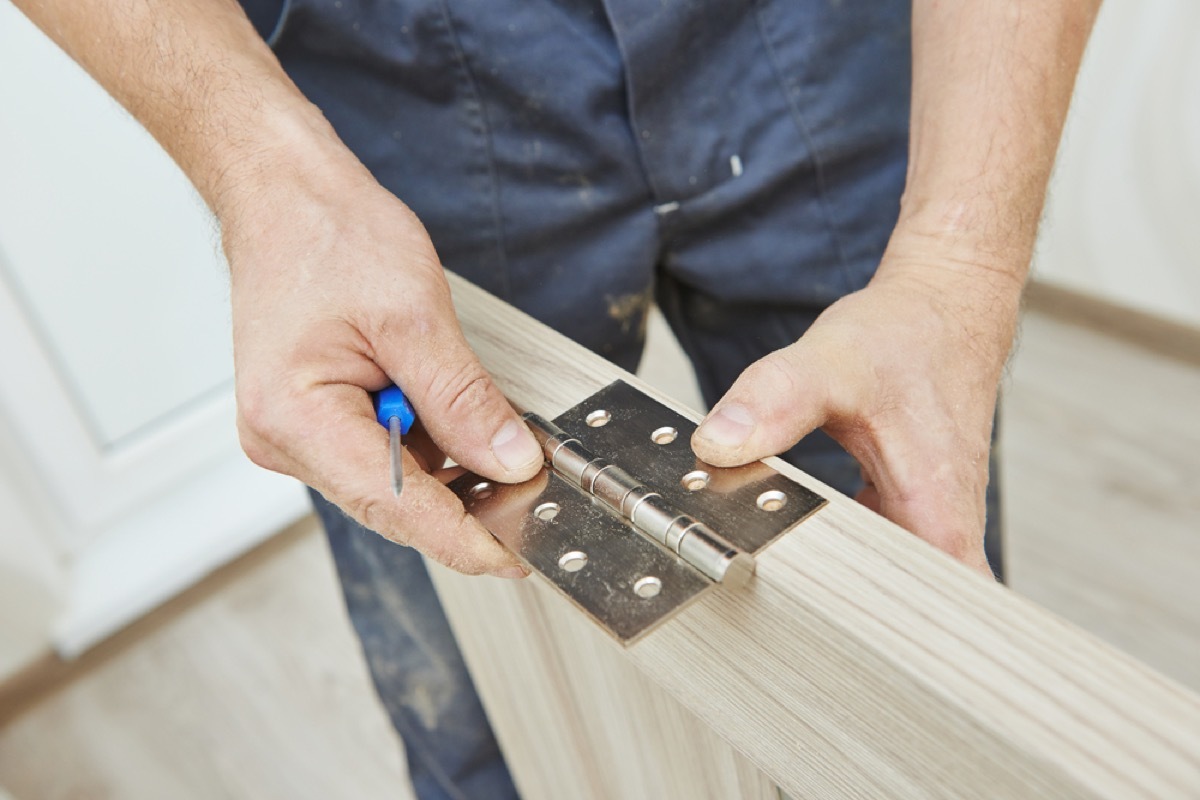 man repairing hinge on door