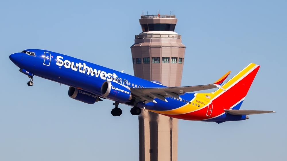 A Southwest Airlines airliner taking off with an air control tower in the background