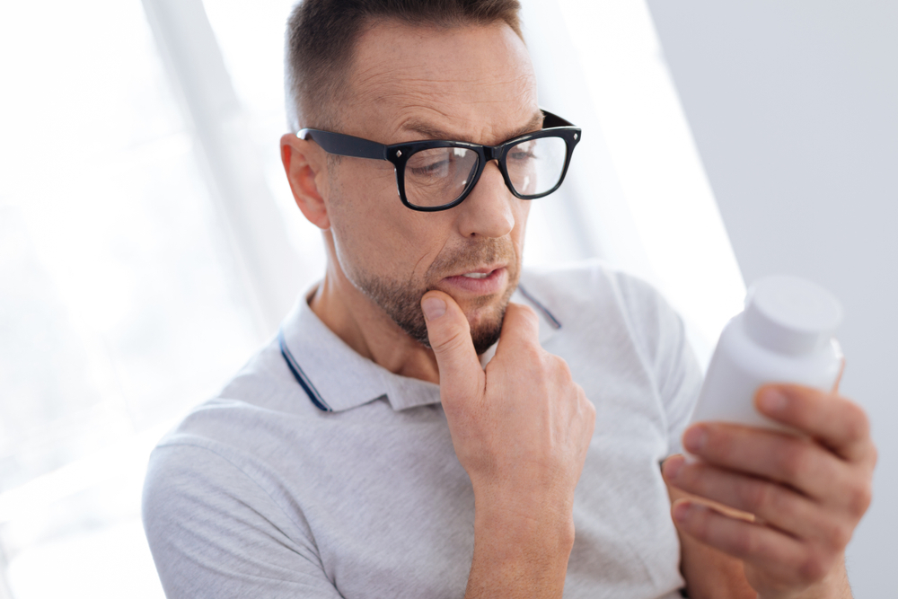 A man checking the label on a supplement bottle