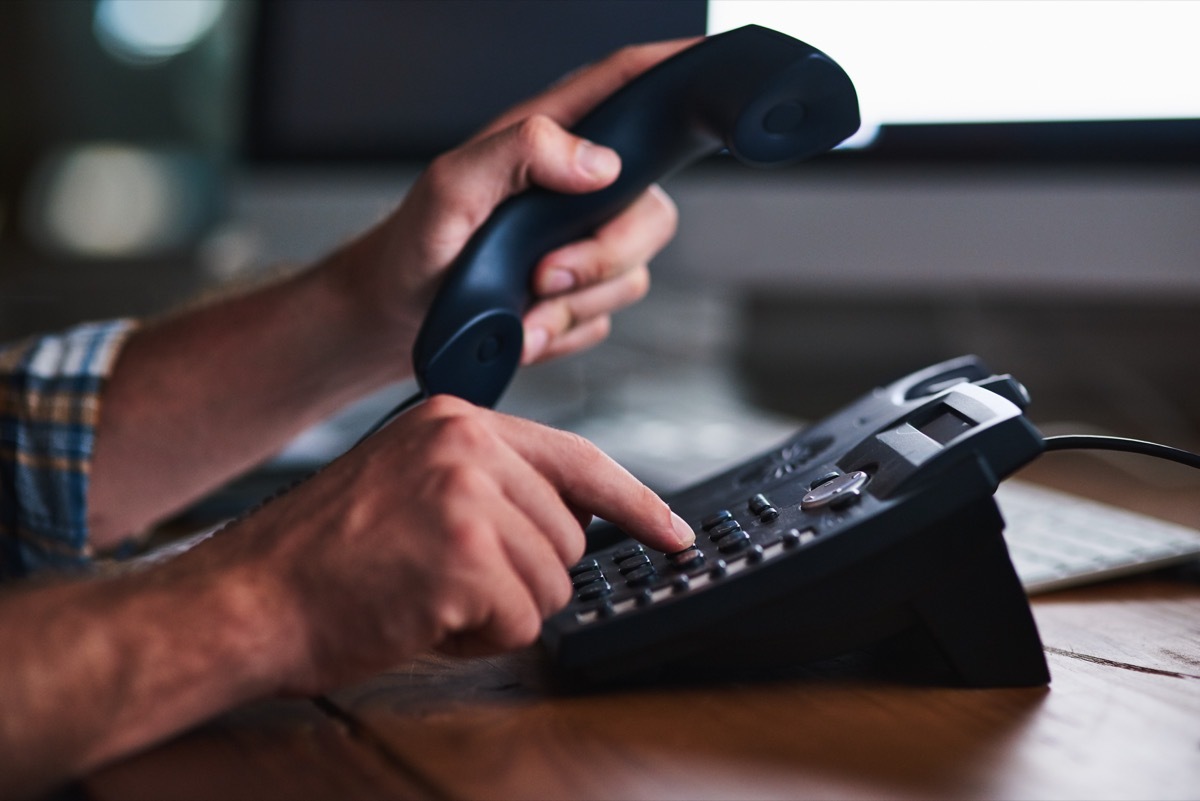 man calling and dialing on a landline phone