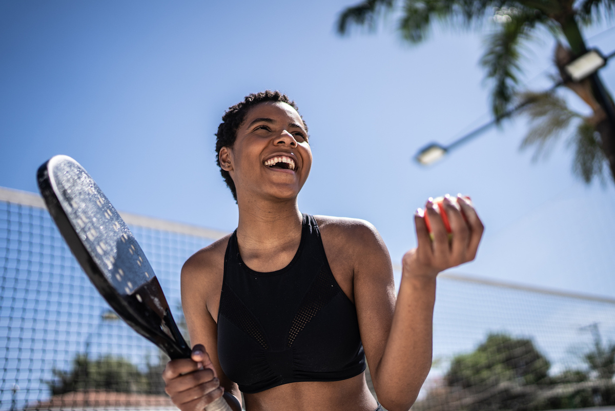 Happy woman celebrating during beach tennis match