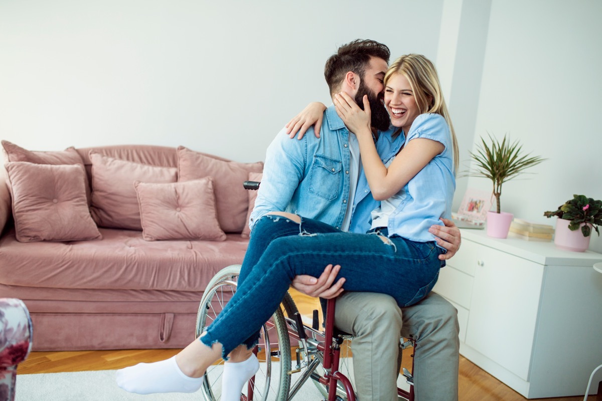 bearded man in wheelchair holding girlfriend on lap