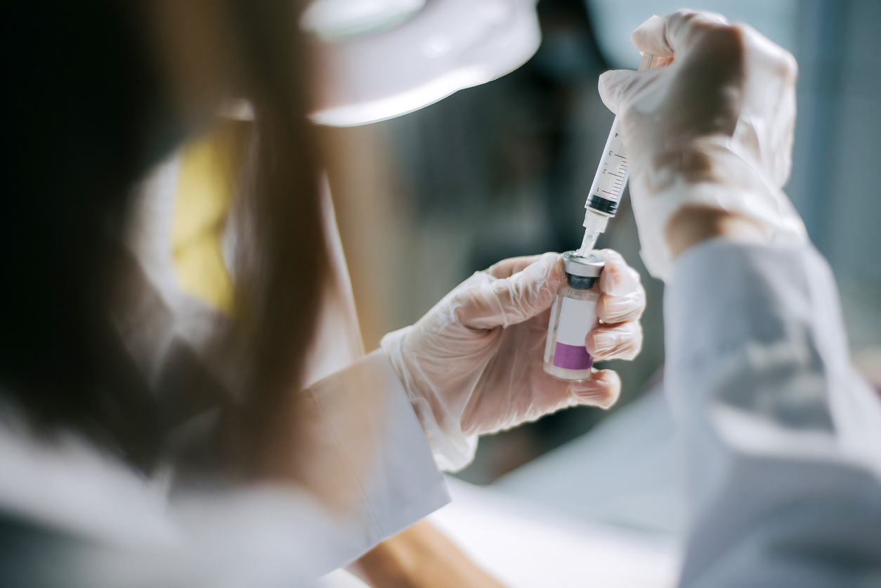 Hand holding a syringe and a bottle.