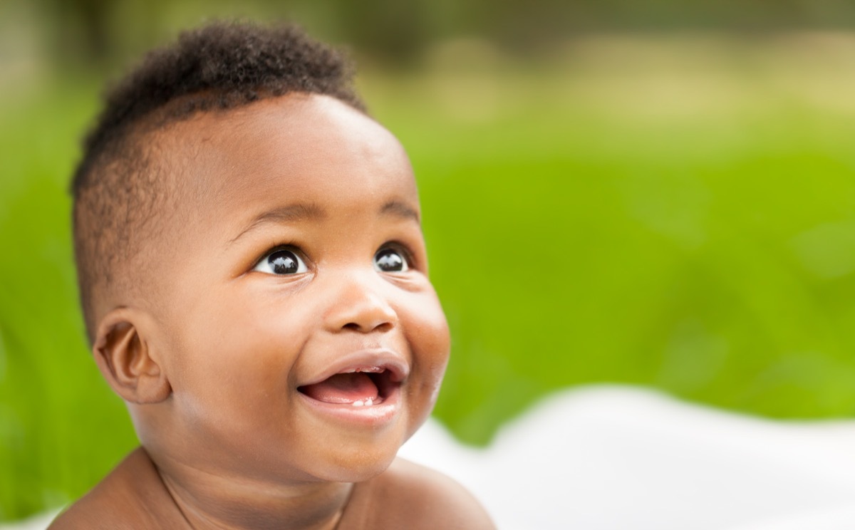 Cheerful little baby smiling while looking away. Horizontal Shot.