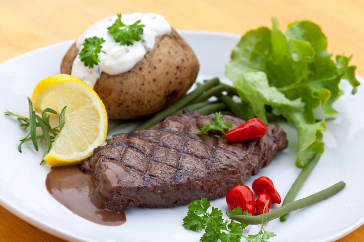 steak and baked potato, lemon, lettuce, place