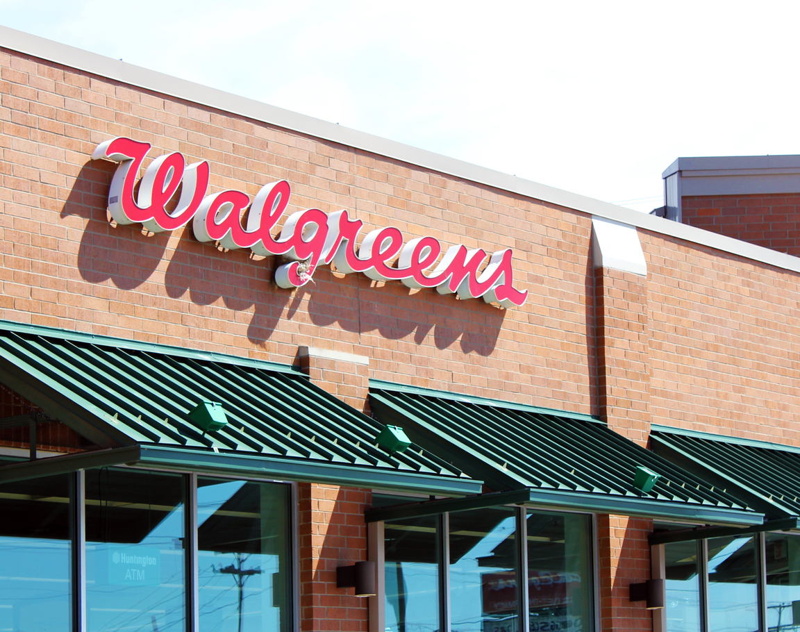 The storefront of a Walgreens pharmacy with red lettering and a green awning