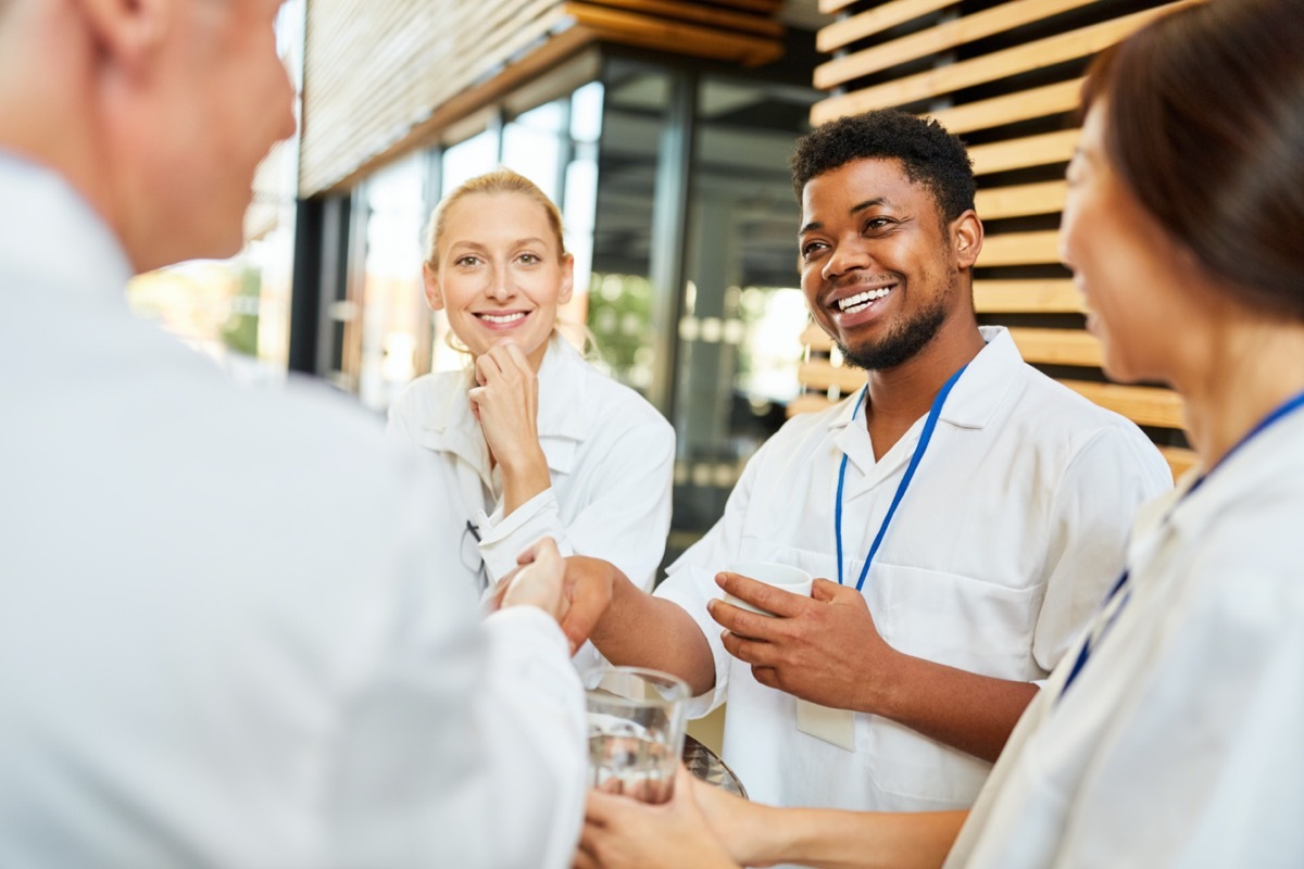 student welcomes senior doctor with handshake in coffee break