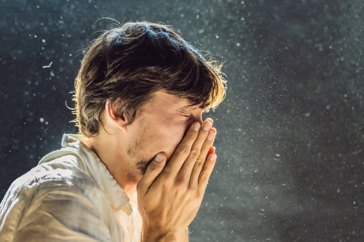 white man sneezing with droplets in the air