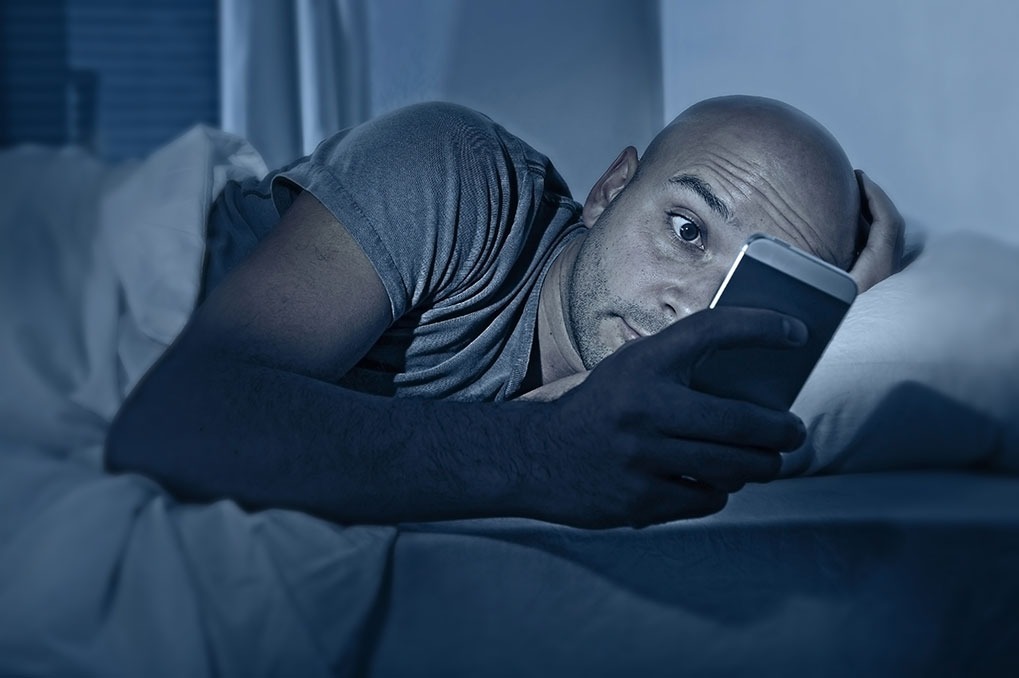 man looking at phone in bed husband mistakes