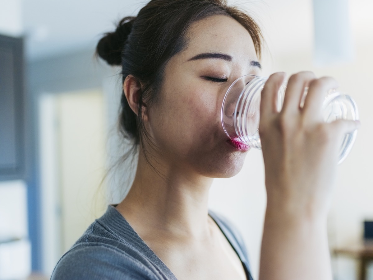 woman drinking water at kitchen.