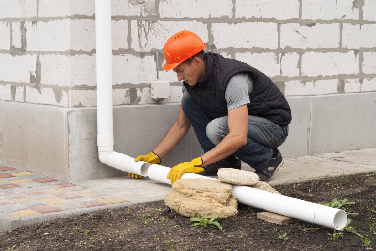 man installing downspout extension, property damage