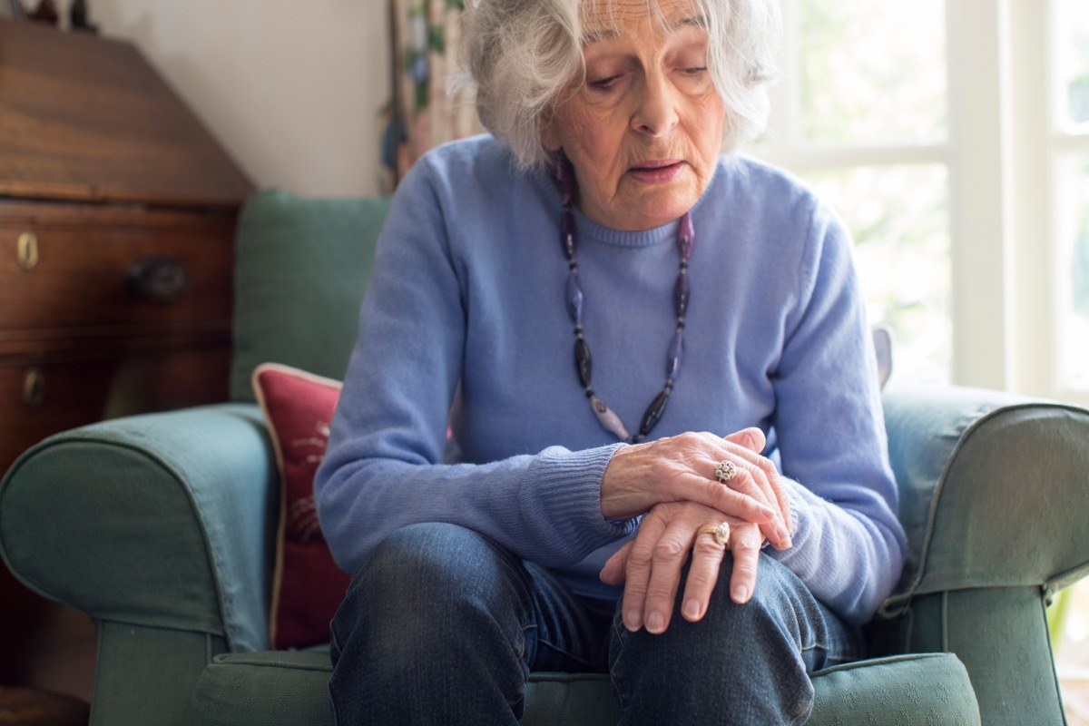 older woman steadying her hand Parkinson's disease concern