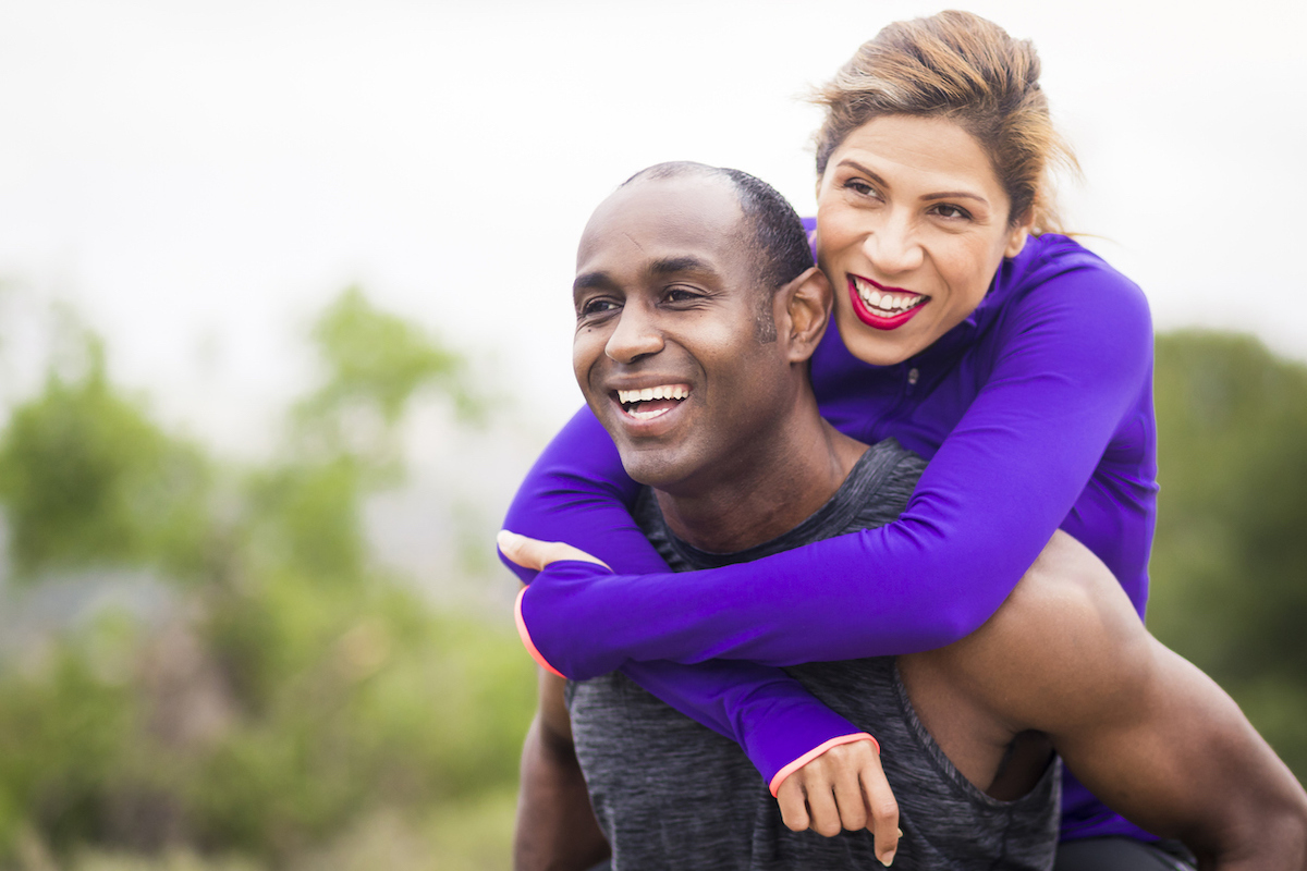 Couple in workout clothes embracing outside, she is wearing a purple top