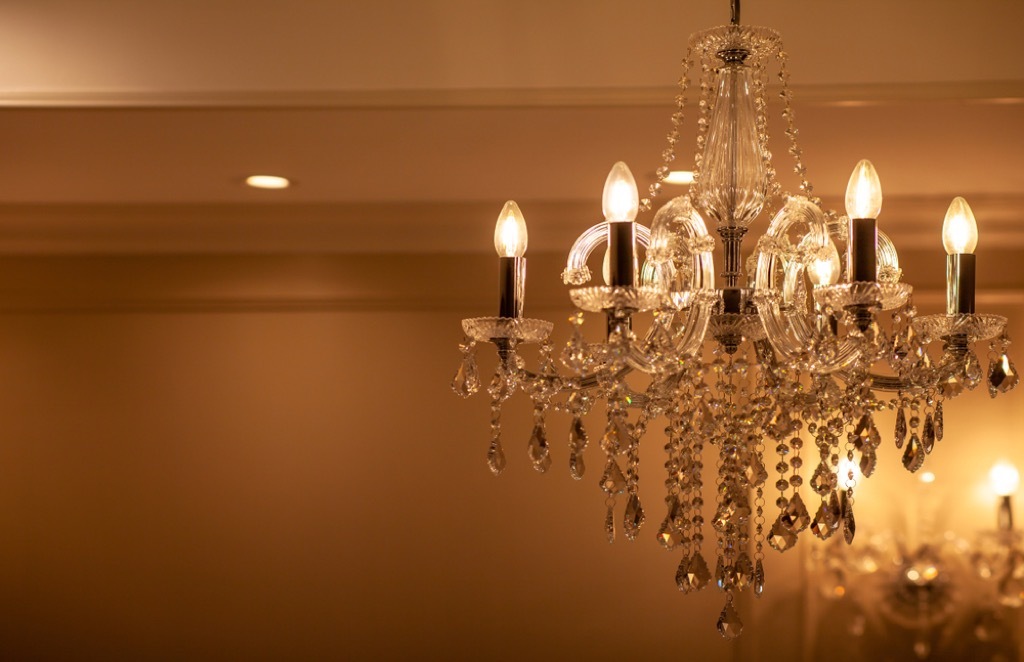 small crystal chandelier in dimly lit room with overhead can lighting