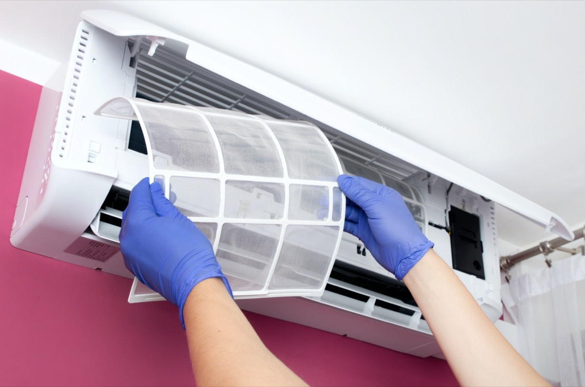 Air conditioner cleaning. Man in gloves checks the filter.