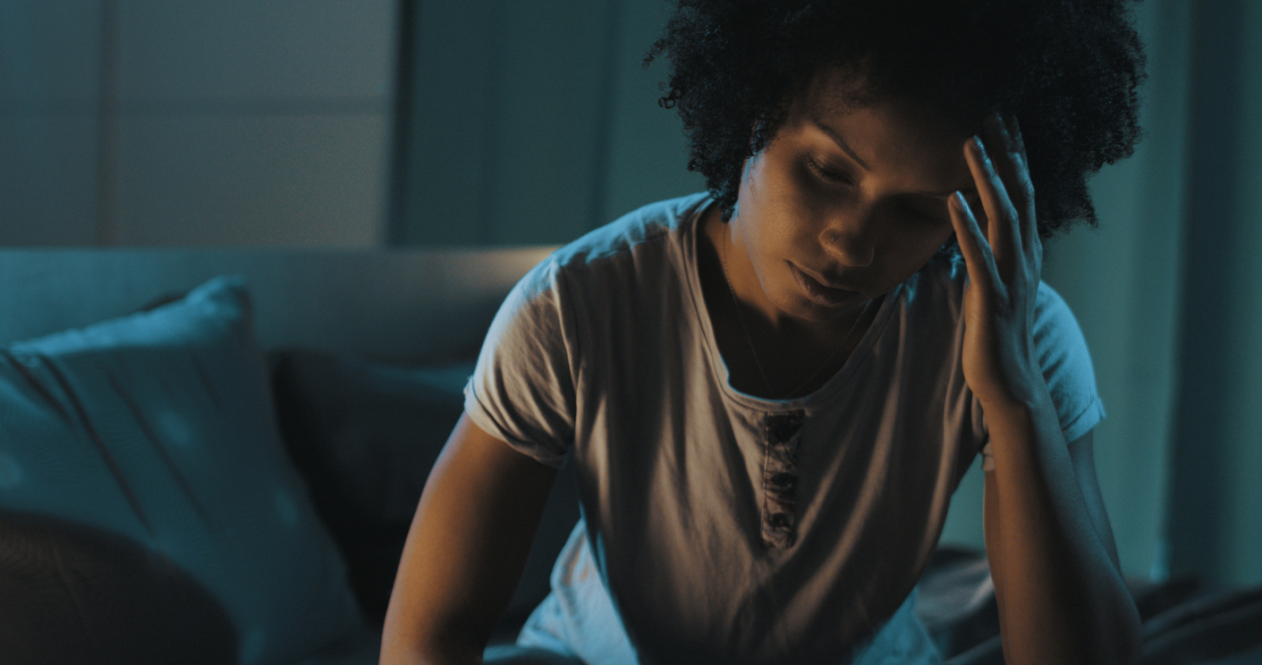 Woman sitting in bed, unable to sleep.