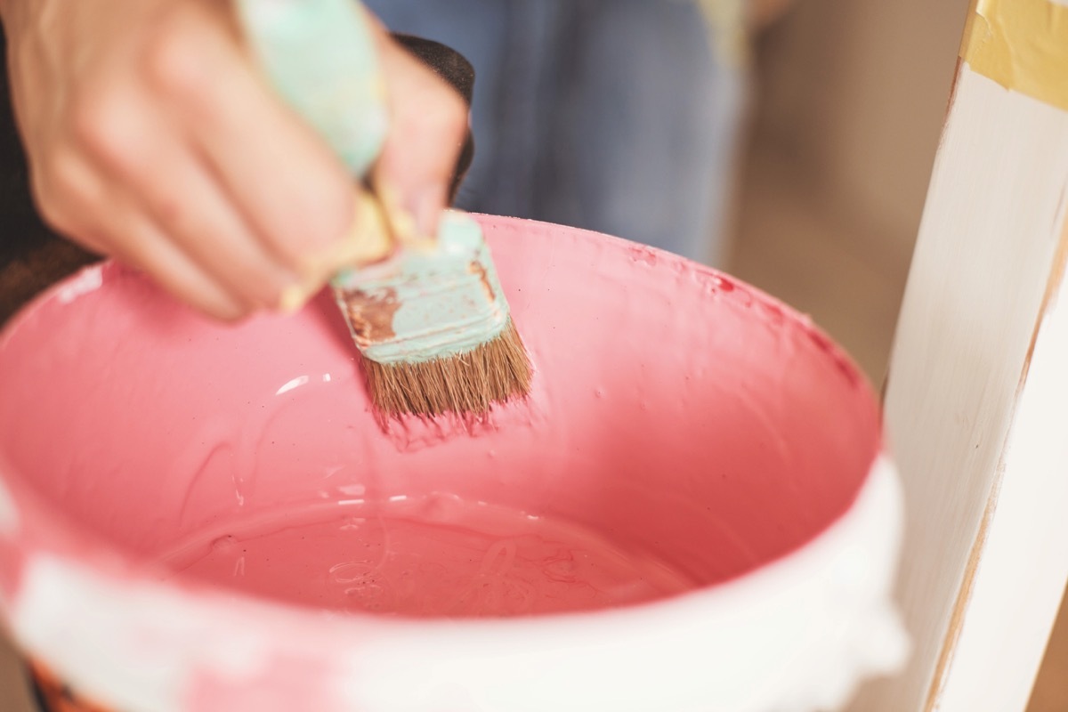 woman dipping brush into paint