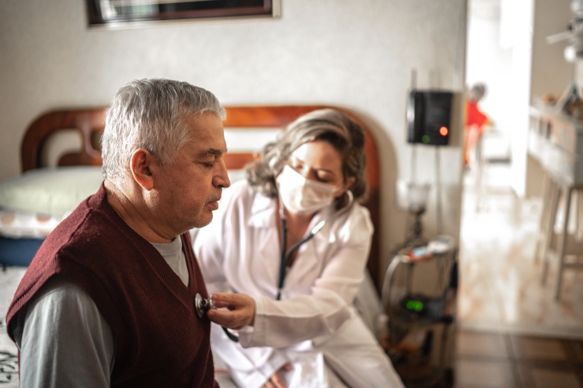 Health visitor using digital tablet and talking to a senior man during home visit