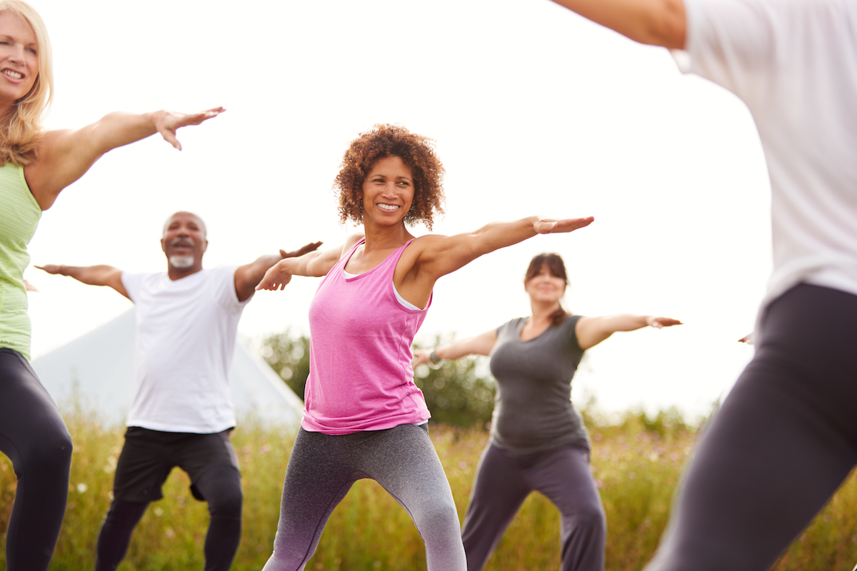 Small group of people in their 40s doing yoga outside