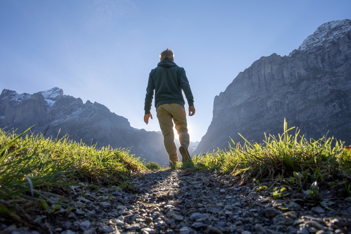 Man hikes along grassy mountain ridge at sunrise