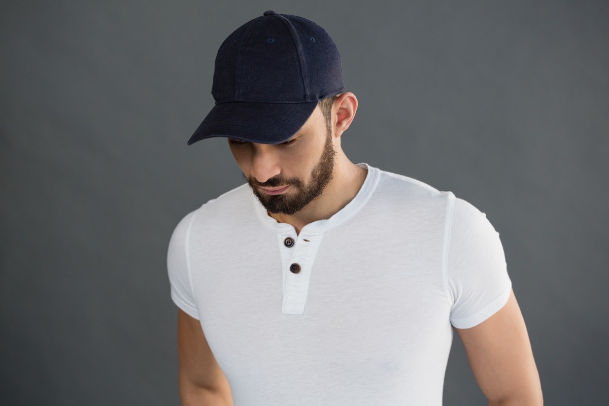 man wearing a white short sleeve henley shirt and a navy ball cap