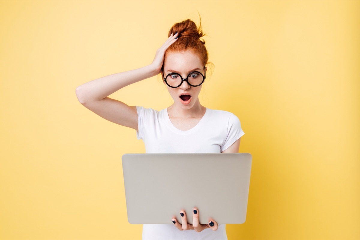 shocked woman with red hair booking cheap flights