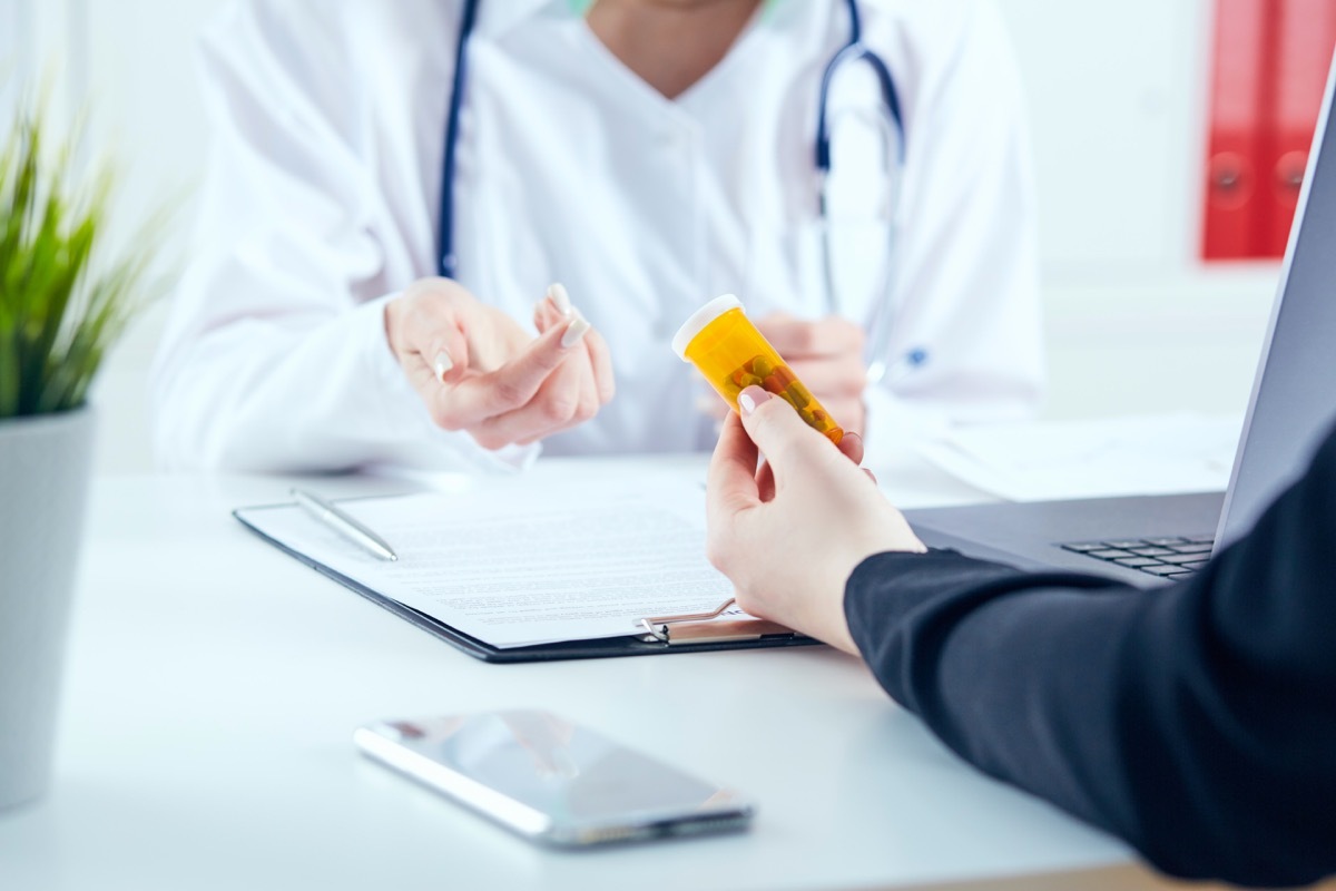 patient holding prescription bottle talking with doctor