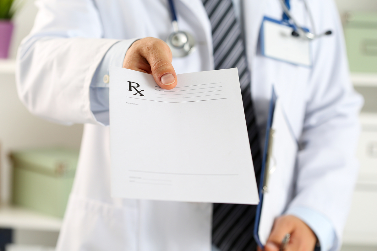 Male doctor hand hold clipboard pad and give prescription to patient