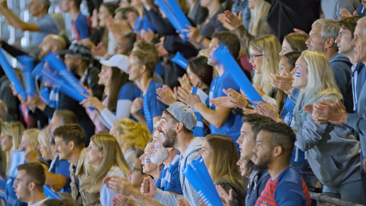 Crowd cheering while watching match in stadium.