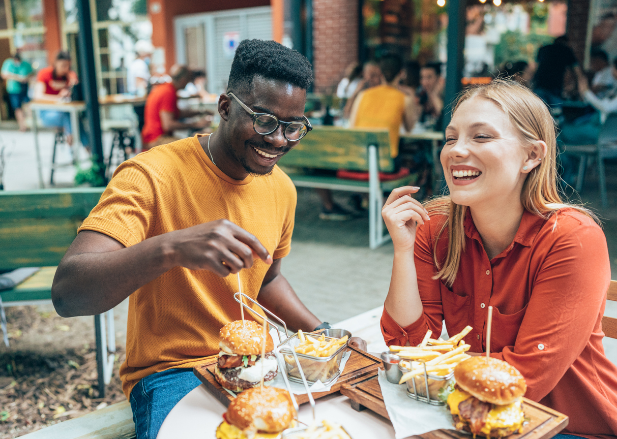 Friends eating burgers and fries and have fun in outdoor restaurant