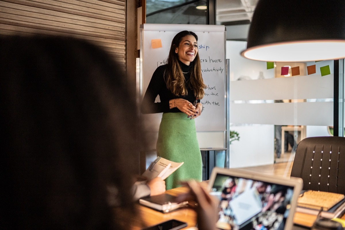 businesswoman giving presentation in green skirt